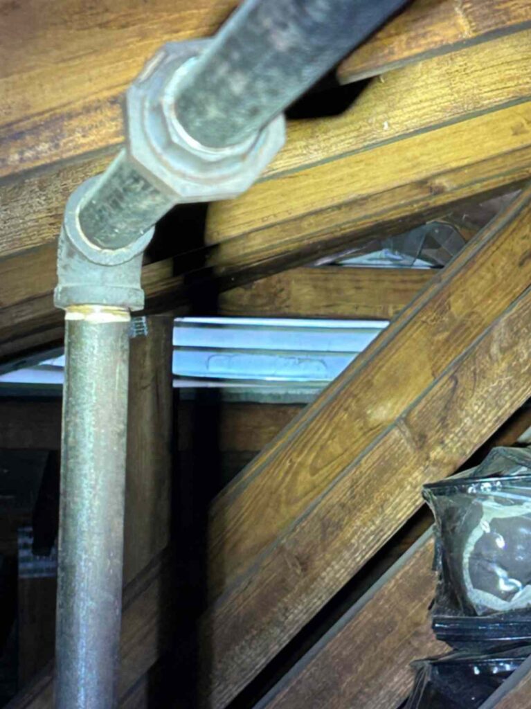 Close-up of an attic with wooden beams and a metal pipe running diagonally, taken during Squirrel Removal in High Point.